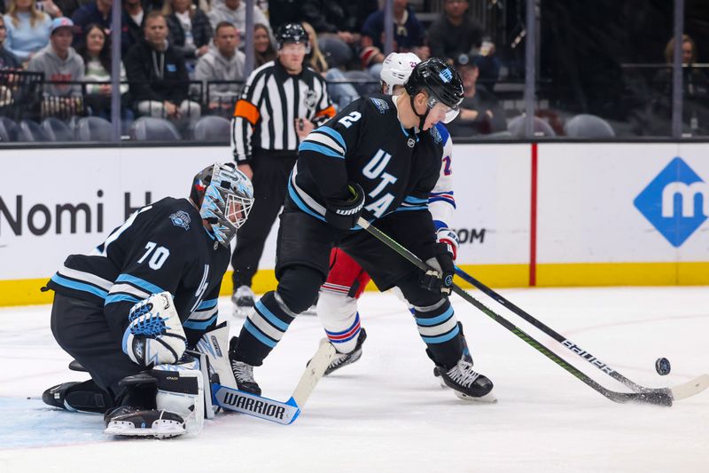 Jan 16, 2025; Salt Lake City, Utah, USA; Utah Hockey Club defenseman Olli Maatta (2) clears the puck for goaltender Karel Vejmelka (70) against the New York Rangers during the third period at Delta Center. Mandatory Credit: Rob Gray-Imagn Images