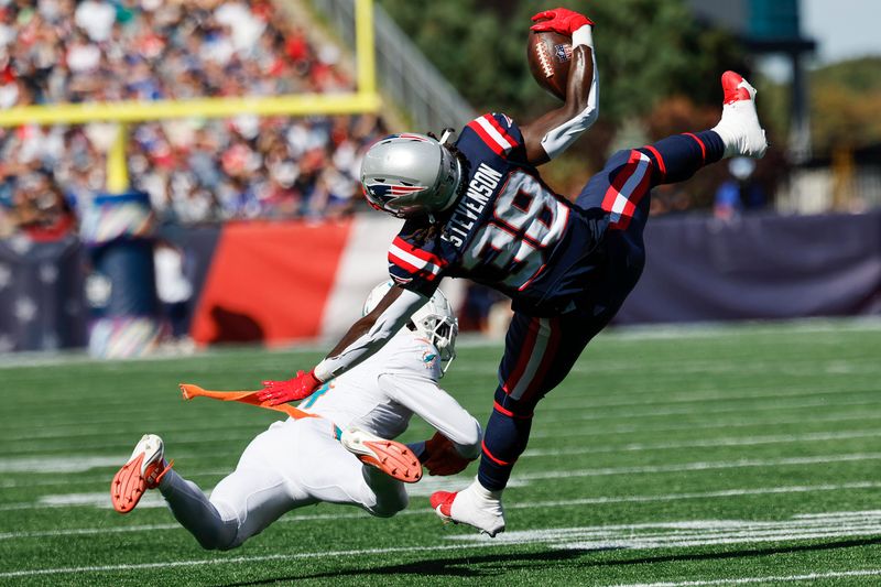 New England Patriots running back Rhamondre Stevenson (38) is up ended by Miami Dolphins cornerback Kader Kohou (4) during the first half of an NFL football game on Sunday, Oct. 6, 2024, in Foxborough, Mass. (AP Photo/Greg M. Cooper)