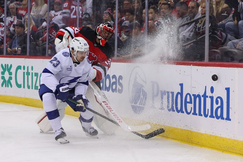 Oct 22, 2024; Newark, New Jersey, USA; New Jersey Devils goaltender Jake Allen (34) plays the puck away from Tampa Bay Lightning center Michael Eyssimont (23) during the first period at Prudential Center. Mandatory Credit: Ed Mulholland-Imagn Images