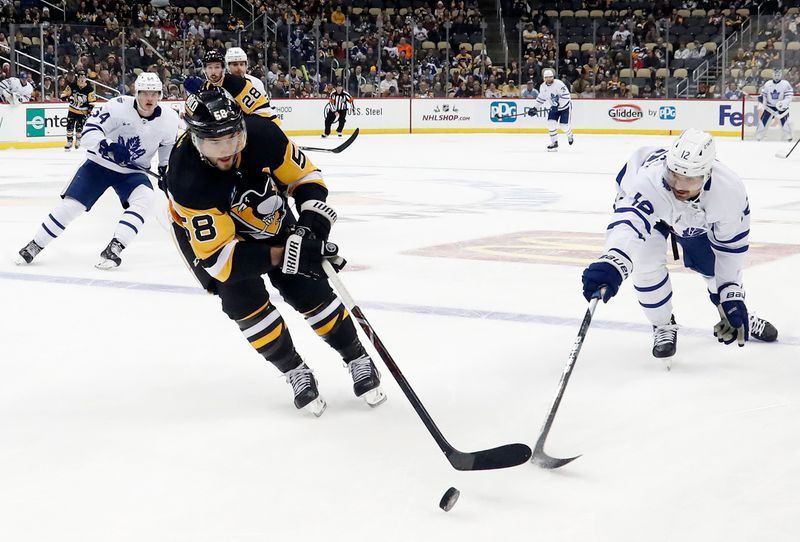 Nov 26, 2022; Pittsburgh, Pennsylvania, USA; Pittsburgh Penguins defenseman Kris Letang (58) reaches for the puck against Toronto Maple Leafs center Zach Aston-Reese (12) during the third period at PPG Paints Arena. Toronto won 4-1. Mandatory Credit: Charles LeClaire-USA TODAY Sports