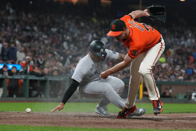 May 31, 2024; San Francisco, California, USA; New York Yankees first baseman Anthony Rizzo (left) scores a run as San Francisco Giants relief pitcher Taylor Rogers (right) is unable to catch a throw during the sixth inning at Oracle Park. Mandatory Credit: Darren Yamashita-USA TODAY Sports