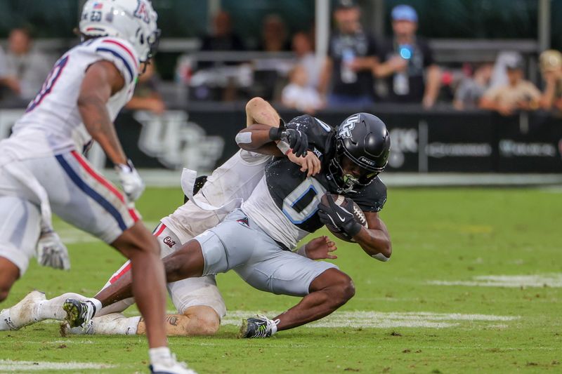 Nov 2, 2024; Orlando, Florida, USA; UCF Knights running back Johnny Richardson (0) is tackled by Arizona Wildcats defensive back Jack Luttrell (13) during the second half at FBC Mortgage Stadium. Mandatory Credit: Mike Watters-Imagn Images