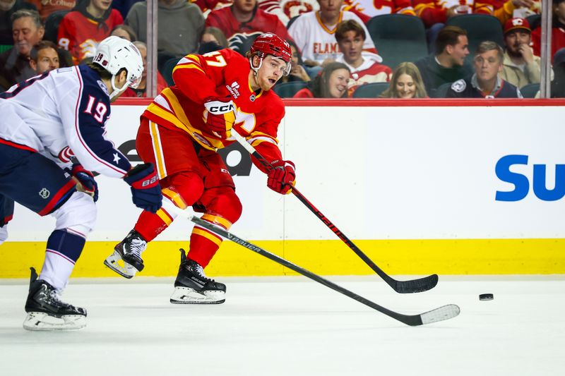 Nov 5, 2025; Calgary, Alberta, CAN; Calgary Flames center Connor Zary (47) passes the puck in front of Columbus Blue Jackets center Adam Fantilli (19) during the first period at Scotiabank Saddledome. Mandatory Credit: Sergei Belski-Imagn Images