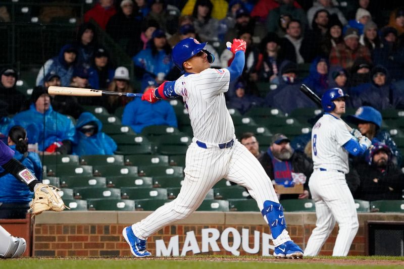 Apr 3, 2024; Chicago, Illinois, USA; Chicago Cubs catcher Miguel Amaya (9) hits a one run sacrifice fly against the Colorado Rockies during the second inning at Wrigley Field. Mandatory Credit: David Banks-USA TODAY Sports