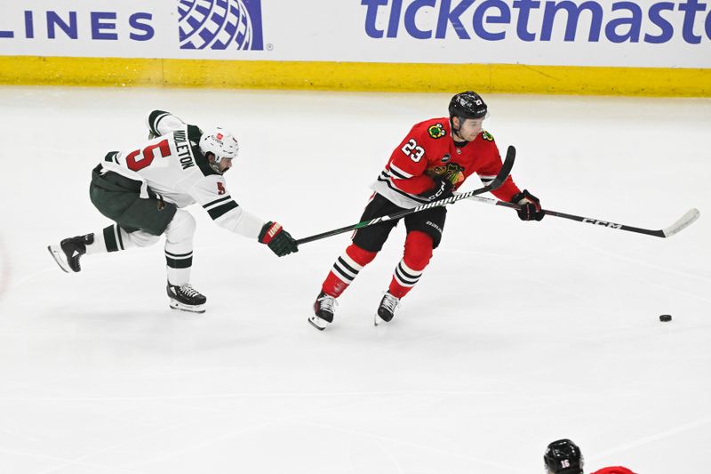 Apr 7, 2024; Chicago, Illinois, USA;  Chicago Blackhawks center Philipp Kurashev (23) and Minnesota Wild defenseman Jake Middleton (5)  chase the puck during the first period at United Center. Mandatory Credit: Matt Marton-USA TODAY Sports