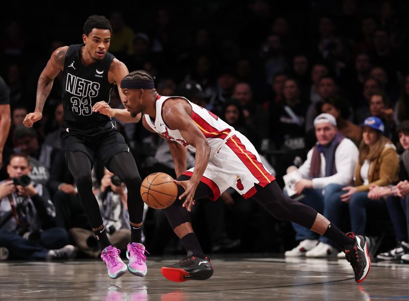 NEW YORK, NEW YORK - JANUARY 15:  Jimmy Butler #22 of the Miami Heat drives against Nic Claxton #33 of the Brooklyn Nets during their game at Barclays Center on January 15, 2024 in New York City.   User expressly acknowledges and agrees that, by downloading and or using this photograph, User is consenting to the terms and conditions of the Getty Images License Agreement.  (Photo by Al Bello/Getty Images)