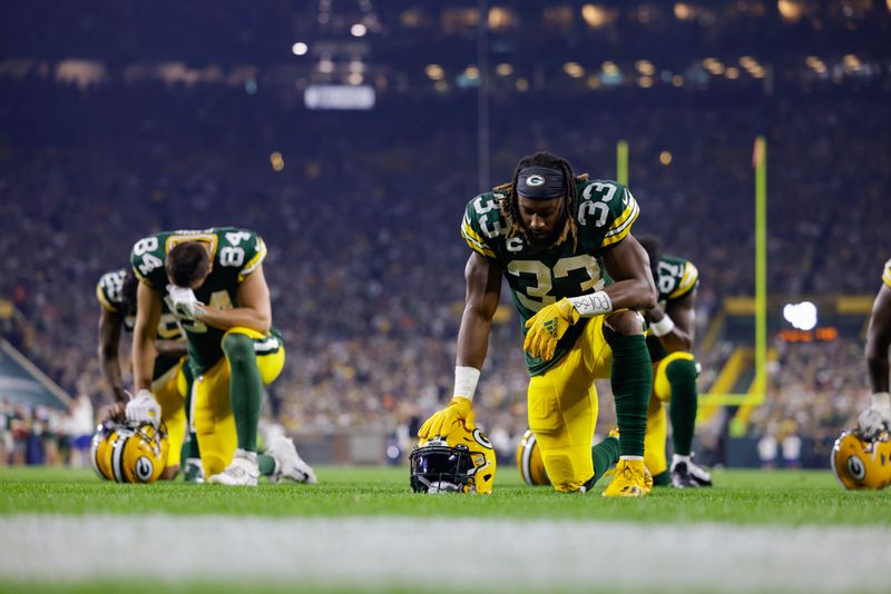 Green Bay Packers running back Aaron Jones (33) kneels with teammates in the end zone prior to the start of an NFL football game against the Chicago Bears Sunday, Sept. 18, 2022, in Green Bay, Wis. (AP Photo/Matt Ludtke)