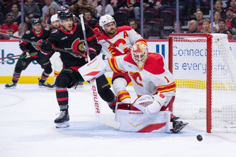 Oct 30, 2025; Ottawa, Ontario, CAN; Calgary Flames goalie Devin Cooley (1) makes a save in front of Ottawa Senators center Dylan Cozens (24) in the first period at the Canadian Tire Centre. Mandatory Credit: Marc DesRosiers-IMAGN Images