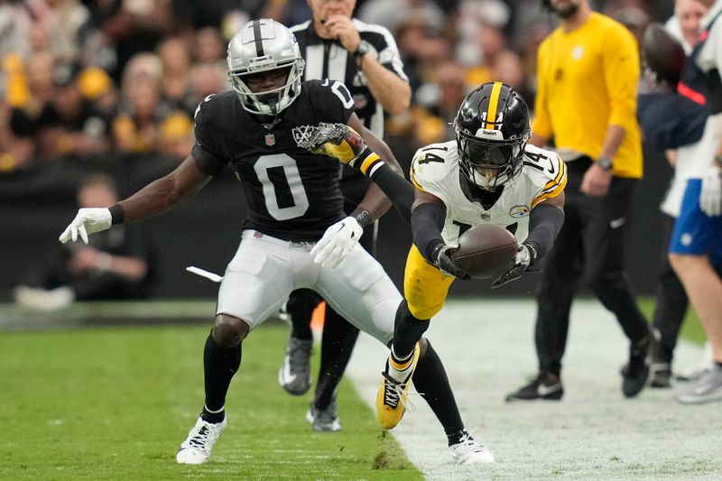 Pittsburgh Steelers wide receiver George Pickens (14) dives forward after catching a pass in front of Las Vegas Raiders cornerback Jakorian Bennett (0) during the first half of an NFL football game in Las Vegas, Sunday, Oct. 13, 2024. (AP Photo/John Locher)