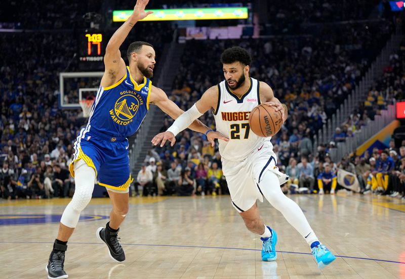 SAN FRANCISCO, CALIFORNIA - FEBRUARY 25: Jamal Murray #27 of the Denver Nuggets dribbles the ball while being guarded by Stephen Curry #30 of the Golden State Warriors in the first quarter of an NBA basketball game at Chase Center on February 25, 2024 in San Francisco, California. NOTE TO USER: User expressly acknowledges and agrees that, by downloading and or using this photograph, User is consenting to the terms and conditions of the Getty Images License Agreement. (Photo by Thearon W. Henderson/Getty Images)