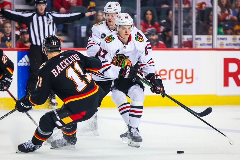 Jan 27, 2024; Calgary, Alberta, CAN; Chicago Blackhawks left wing Lukas Reichel (27) and Calgary Flames center Mikael Backlund (11) battles for the puck during the third period at Scotiabank Saddledome. Mandatory Credit: Sergei Belski-USA TODAY Sports