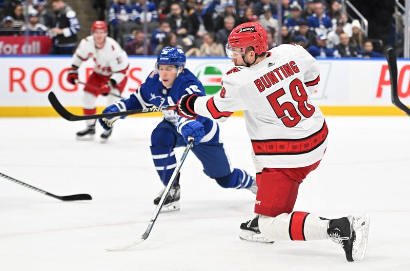 Dec 30, 2023; Toronto, Ontario, CAN; Carolina Hurricanes forward Michael Bunting (58) shoots the puck past Toronto Maple Leafs forward Mitchell Marner (16) in the second period at Scotiabank Arena. Mandatory Credit: Dan Hamilton-USA TODAY Sports