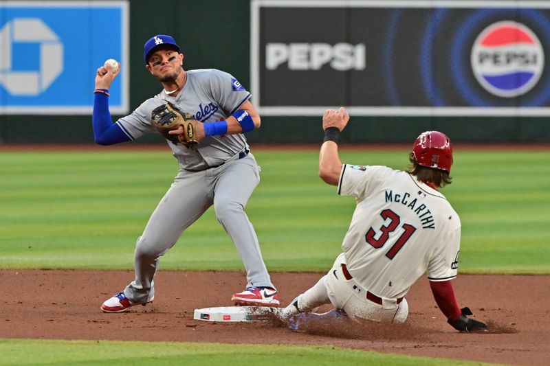 May 1, 2024; Phoenix, Arizona, USA;  Los Angeles Dodgers shortstop Miguel Rojas (11) turns a double play on Arizona Diamondbacks outfielder Jake McCarthy (31) in the first inning at Chase Field. Mandatory Credit: Matt Kartozian-USA TODAY Sports