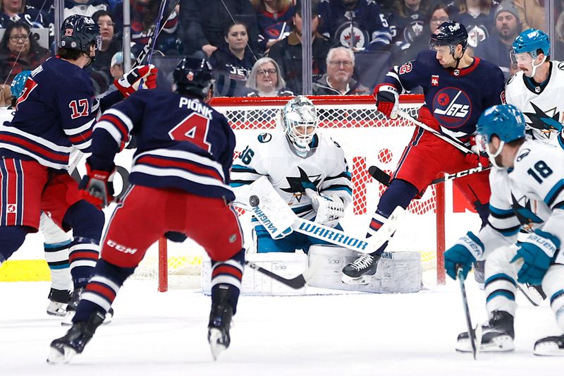 Feb 14, 2024; Winnipeg, Manitoba, CAN; Winnipeg Jets defenseman Neal Pionk (4) takes a shot on San Jose Sharks goaltender Kaapo Kahkonen (36) in the first period at Canada Life Centre. Mandatory Credit: James Carey Lauder-USA TODAY Sports