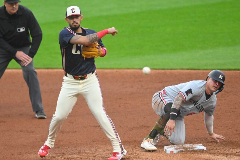 May 17, 2024; Cleveland, Ohio, USA; Cleveland Guardians shortstop Gabriel Arias (13) turns a double play beside Minnesota Twins third baseman Jose Miranda (64) in the third inning at Progressive Field. Mandatory Credit: David Richard-USA TODAY Sports