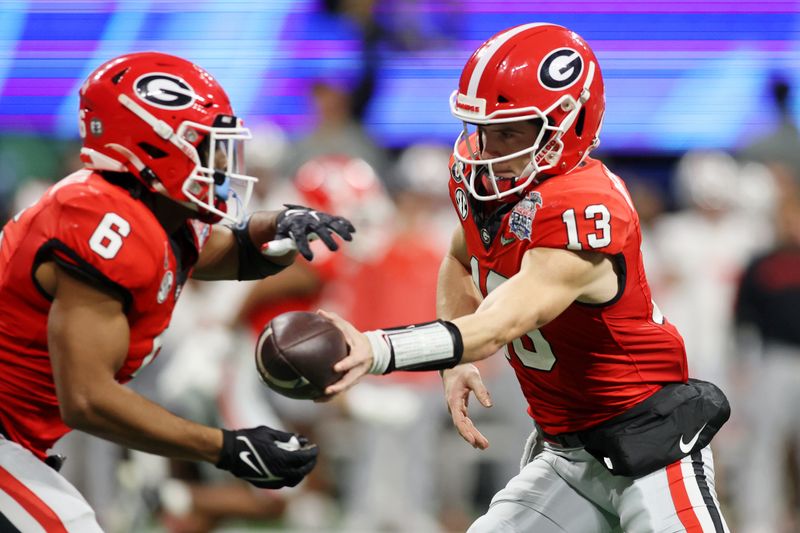 Dec 31, 2022; Atlanta, Georgia, USA; Georgia Bulldogs quarterback Stetson Bennett (13) hands the ball off to running back Kenny McIntosh (6) against the Ohio State Buckeyes during the third quarter of the 2022 Peach Bowl at Mercedes-Benz Stadium. Mandatory Credit: Brett Davis-USA TODAY Sports