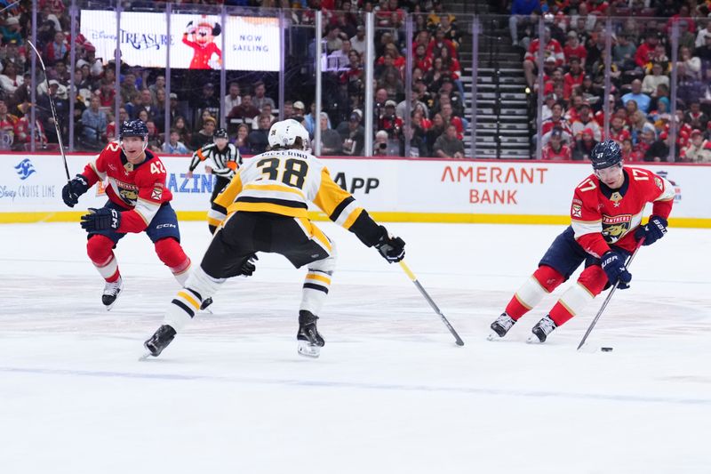 Jan 3, 2025; Sunrise, Florida, USA; Florida Panthers center Evan Rodrigues (17) skates the puck up the ice against Pittsburgh Penguins defenseman Owen Pickering (38) during the first period at Amerant Bank Arena. Mandatory Credit: Rich Storry-Imagn Images