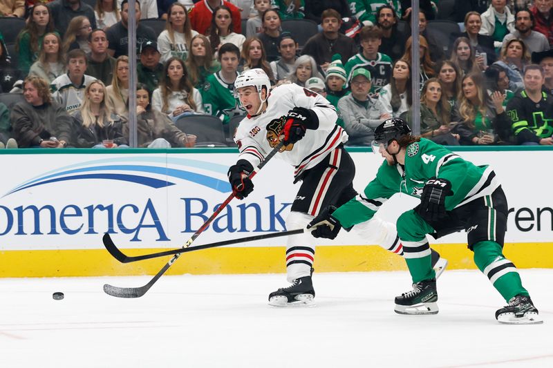 Dec 27, 2025; Dallas, Texas, USA; Chicago Blackhawks defenseman Louis Crevier (46) shoots the puck against Dallas Stars defenseman Miro Heiskanen (4) during the first period at American Airlines Center. Mandatory Credit: Chris Jones-Imagn Images