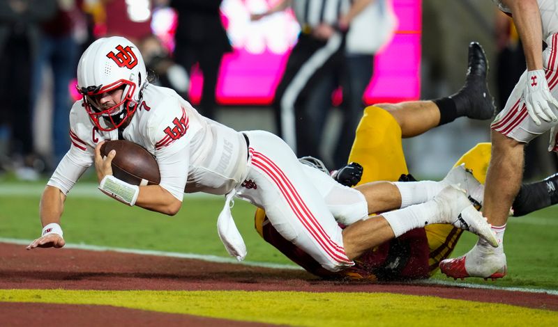 Oct 9, 2021; Los Angeles, California, USA; Utah Utes quarterback Cameron Rising (7) dives into the end zone to score a third quarter touchdown in the grasp of USC Trojans defensive lineman Nick Figueroa (50) at United Airlines Field at Los Angeles Memorial Coliseum. Mandatory Credit: Robert Hanashiro-USA TODAY Sports