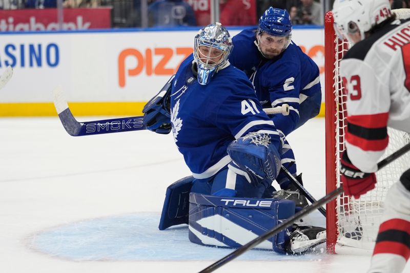Oct 21, 2025; Toronto, Ontario, CAN; Toronto Maple Leafs goaltender Anthony Stolarz (41) and defenseman Simon Benoit (2) defend the goal against New Jersey Devils defenseman Luke Hughes (43) during the second period at Scotiabank Arena. Mandatory Credit: John E. Sokolowski-Imagn Images