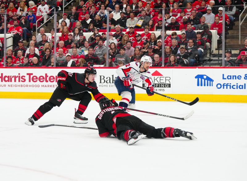 May 12, 2025; Raleigh, North Carolina, USA; Washington Capitals right wing Brandon Duhaime (22) watches his shot against Carolina Hurricanes right wing Jackson Blake (53) and defenseman Shayne Gostisbehere (4) during the second period in game four of the second round of the 2025 Stanley Cup Playoffs at Lenovo Center. Mandatory Credit: James Guillory-Imagn Images