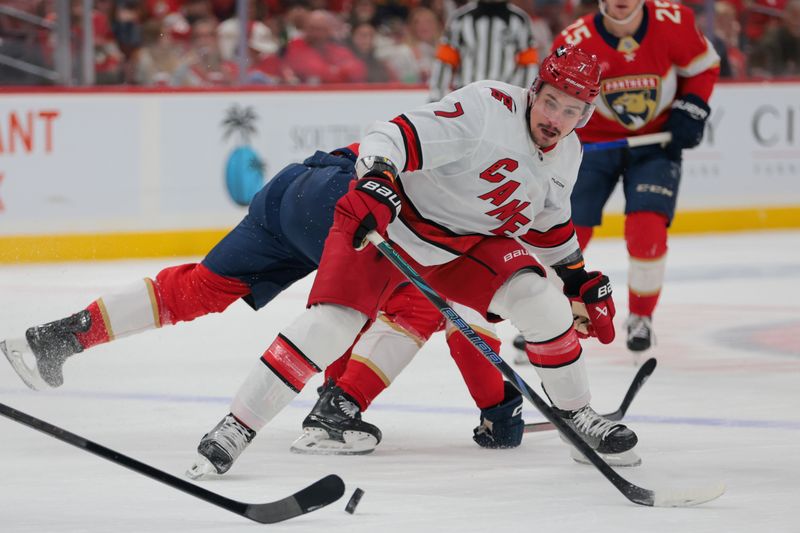 Nov 30, 2024; Sunrise, Florida, USA; Carolina Hurricanes defenseman Dmitry Orlov (7) battles for the puck against the Florida Panthers during the first period at Amerant Bank Arena. Mandatory Credit: Sam Navarro-Imagn Images