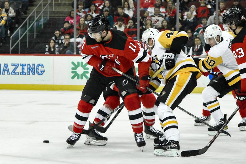 Apr 2, 2024; Newark, New Jersey, USA; New Jersey Devils center Chris Tierney (11) competes for the puck with Pittsburgh Penguins right wing Valtteri Puustinen (48) during the first period at Prudential Center. Mandatory Credit: John Jones-USA TODAY Sports