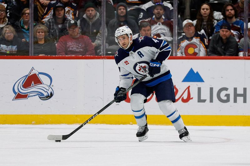 Jan 22, 2025; Denver, Colorado, USA; Winnipeg Jets defenseman Neal Pionk (4) controls the puck in the third period against the Colorado Avalanche at Ball Arena. Mandatory Credit: Isaiah J. Downing-Imagn Images