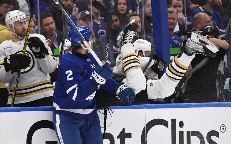 May 2, 2024; Toronto, Ontario, CAN;   Boston Bruins forward Justin Brazeau (55) flips over the boards of the Bruins bench after missing a bodycheck on Toronto Maple Leafs defenseman Simon Benoit (2) in the first period in game six of the first round of the 2024 Stanley Cup Playoffs at Scotiabank Arena. Mandatory Credit: Dan Hamilton-USA TODAY Sports