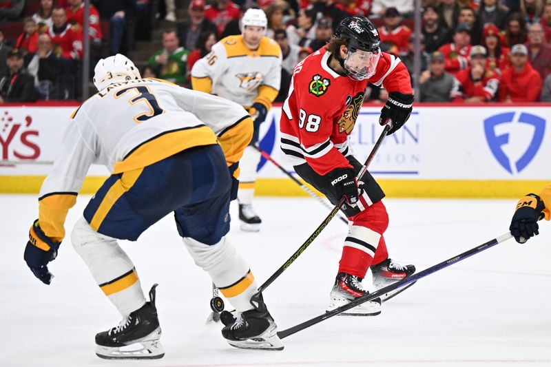 Apr 12, 2024; Chicago, Illinois, USA; Chicago Blackhawks forward Connor Bedard (98) has the puck knocked from his stick by Nashville Predators defenseman Jeremy Lauzon (3) in the second period at United Center. Mandatory Credit: Jamie Sabau-USA TODAY Sports