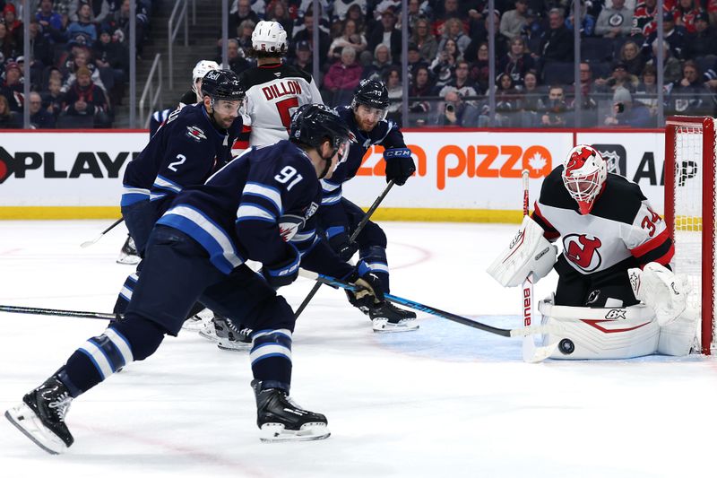 Jan 11, 2026; Winnipeg, Manitoba, CAN; New Jersey Devils goaltender Jake Allen (34) stops a shot by Winnipeg Jets center Cole Perfetti (91) in the second period at Canada Life Centre. Mandatory Credit: James Carey Lauder-Imagn Images
