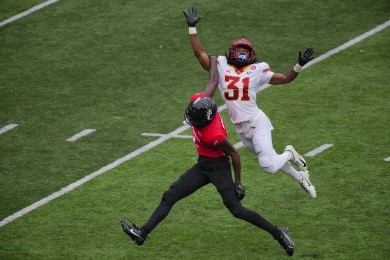 Oct 14, 2023; Cincinnati, Ohio, USA;  Iowa State Cyclones defensive back Jontez Williams (31) leaps to play the ball as he collides with Cincinnati Bearcats wide receiver Dee Wiggins (2) in the second half at Nippert Stadium. Iowa State   s Jontez Williams was called for pass interference on the play. Mandatory Credit: Aaron Doster-USA TODAY Sports