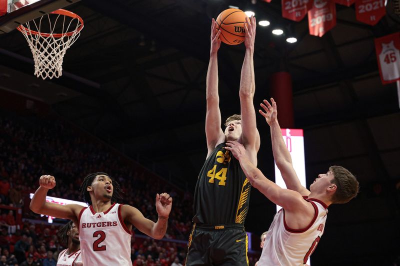 Feb 12, 2025; Piscataway, New Jersey, USA; Iowa Hawkeyes forward Riley Mulvey (44) rebounds against Rutgers Scarlet Knights guard Jordan Derkack (0) and guard Dylan Harper (2) during the first half at Jersey Mike's Arena. Mandatory Credit: Vincent Carchietta-Imagn Images
