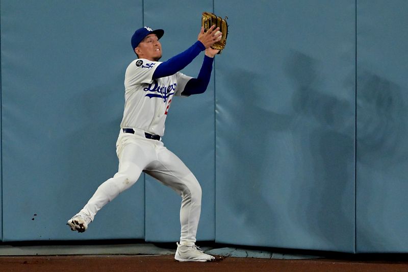 Sep 17, 2025; Los Angeles, California, USA;  Los Angeles Dodgers center fielder Tommy Edman (25) makes a catch at the wall off a ball hit by Philadelphia Phillies catcher J.T. Realmuto (10) in the seventh inning at Dodger Stadium. Mandatory Credit: Jayne Kamin-Oncea-Imagn Images