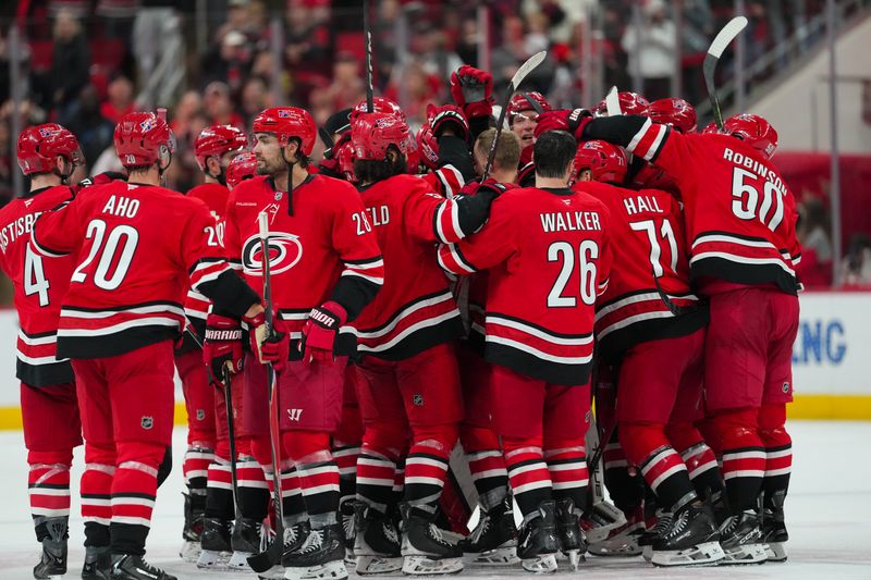 Nov 30, 2025; Raleigh, North Carolina, USA;  Carolina Hurricanes players celebrate their victory against the Calgary Flames in the over time at Lenovo Center. Mandatory Credit: James Guillory-Imagn Images