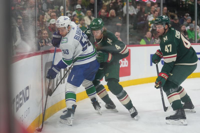 Feb 19, 2024; Saint Paul, Minnesota, USA; Minnesota Wild defenseman Jon Merrill (4) and defenseman Declan Chisholm (47) check Vancouver Canucks center Teddy Blueger (53) in the first period at Xcel Energy Center. Mandatory Credit: Matt Blewett-USA TODAY Sports