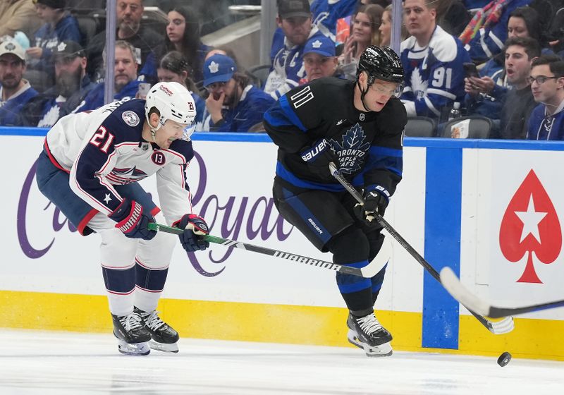 Jan 22, 2025; Toronto, Ontario, CAN; Toronto Maple Leafs center Max Domi (11) battles for the puck with Columbus Blue Jackets left wing James van Riemsdyk (21) during the third period at Scotiabank Arena. Mandatory Credit: Nick Turchiaro-Imagn Images