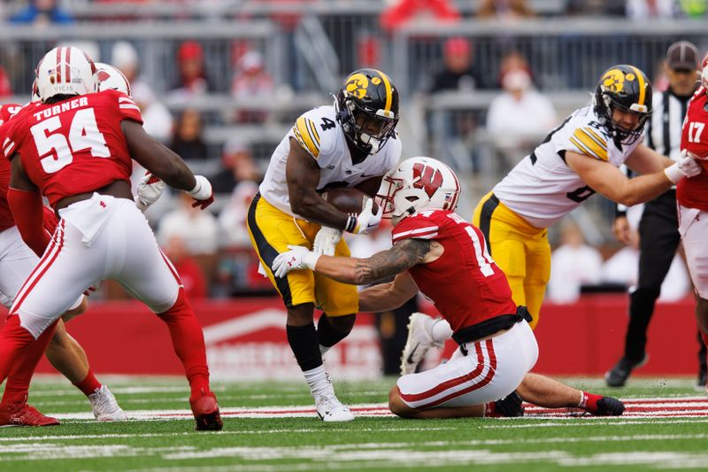 Oct 14, 2023; Madison, Wisconsin, USA;  Iowa Hawkeyes running back Leshon Williams (4) is tackled by Wisconsin Badgers safety Preston Zachman (14) during the first quarter at Camp Randall Stadium. Mandatory Credit: Jeff Hanisch-USA TODAY Sports