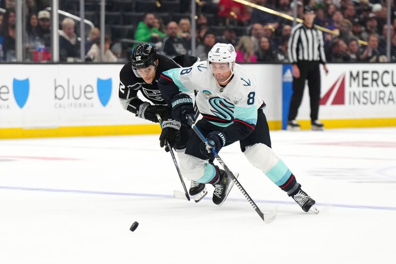 Dec 20, 2023; Los Angeles, California, USA; Seattle Kraken defenseman Brian Dumoulin (8) and LA Kings left wing Trevor Moore (12) reach for the puck in the second period at Crypto.com Arena. Mandatory Credit: Kirby Lee-USA TODAY Sports