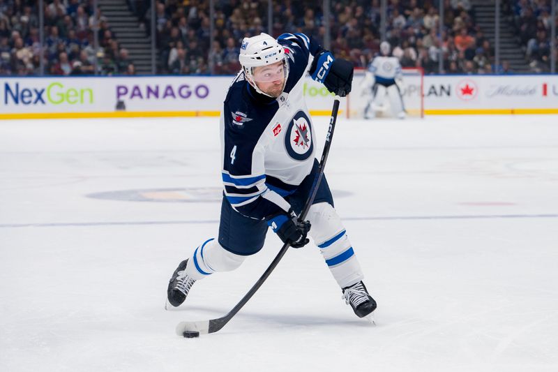 Feb 17, 2024; Vancouver, British Columbia, CAN; Winnipeg Jets defenseman Neal Pionk (4) shoots against the Vancouver Canucks in the third period at Rogers Arena. Jets won 4-2. Mandatory Credit: Bob Frid-USA TODAY Sports