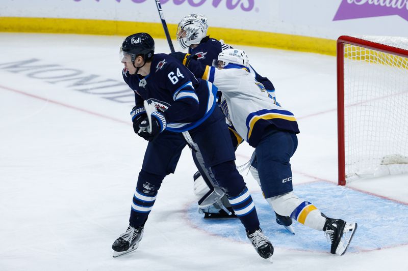 Dec 3, 2024; Winnipeg, Manitoba, CAN;  Winnipeg Jets defenseman Logan Stanley (64) jostles for position with St. Louis Blues forward Mathieu Joseph (71) during the third period at Canada Life Centre. Mandatory Credit: Terrence Lee-Imagn Images