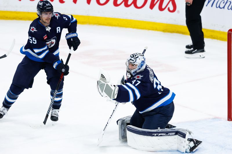 Apr 16, 2024; Winnipeg, Manitoba, CAN;  Winnipeg Jets goalie Connor Hellebuyck (37) makes a save against the Seattle Kraken as Winnipeg Jets forward Mark Scheifele (55) looks for a rebound during the third period at Canada Life Centre. Mandatory Credit: Terrence Lee-USA TODAY Sports