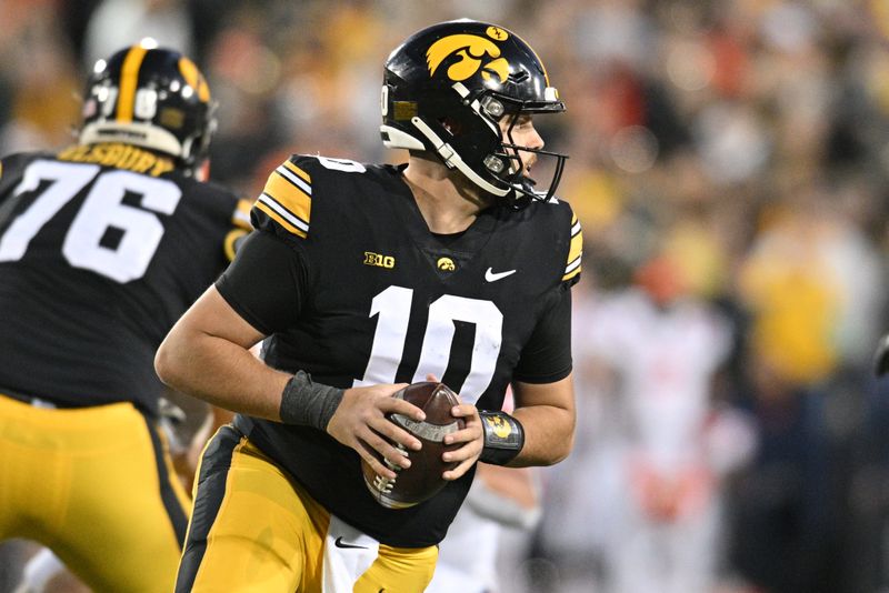 Nov 18, 2023; Iowa City, Iowa, USA; Iowa Hawkeyes quarterback Deacon Hill (10) rolls out against the Illinois Fighting Illini during the third quarter at Kinnick Stadium. Mandatory Credit: Jeffrey Becker-USA TODAY Sports