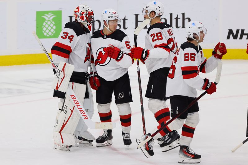 Nov 14, 2024; Sunrise, Florida, USA; New Jersey Devils left wing Jesper Bratt (63) and goaltender Jake Allen (34) celebrate after the game against the Florida Panthers at Amerant Bank Arena. Mandatory Credit: Sam Navarro-Imagn Images