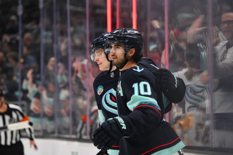 Jan 25, 2025; Seattle, Washington, USA; Seattle Kraken right wing Kaapo Kakko (84) and center Matty Beniers (10) celebrate after Beniers scored a goal against the Pittsburgh Penguins during the third period at Climate Pledge Arena. Mandatory Credit: Steven Bisig-Imagn Images