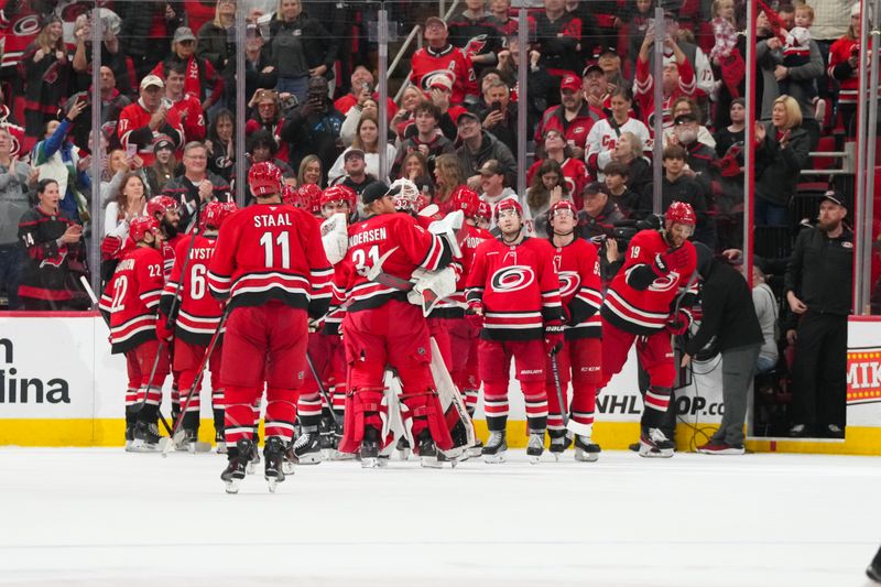 Nov 30, 2025; Raleigh, North Carolina, USA;  Carolina Hurricanes players celebrate their victory against the Calgary Flames in the over time at Lenovo Center. Mandatory Credit: James Guillory-Imagn Images