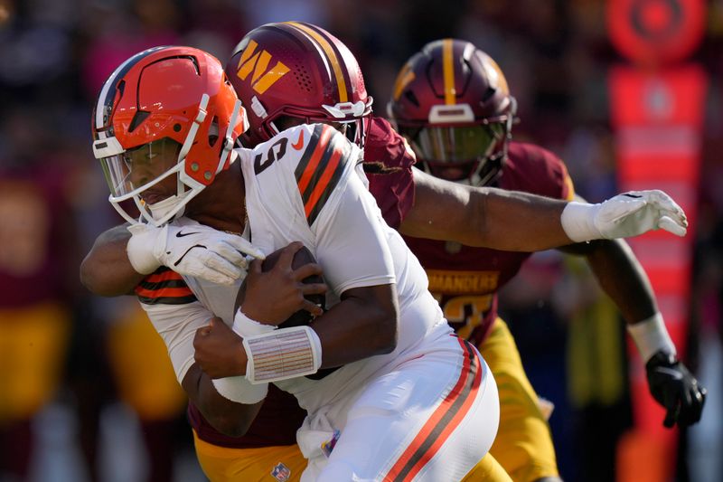 Cleveland Browns quarterback Jameis Winston, front is sacked by Washington Commanders quarterback Jayden Daniels, back, during the second half of an NFL football game in Landover, Md., Sunday, Oct. 6, 2024. (AP Photo/Stephanie Scarbrough)