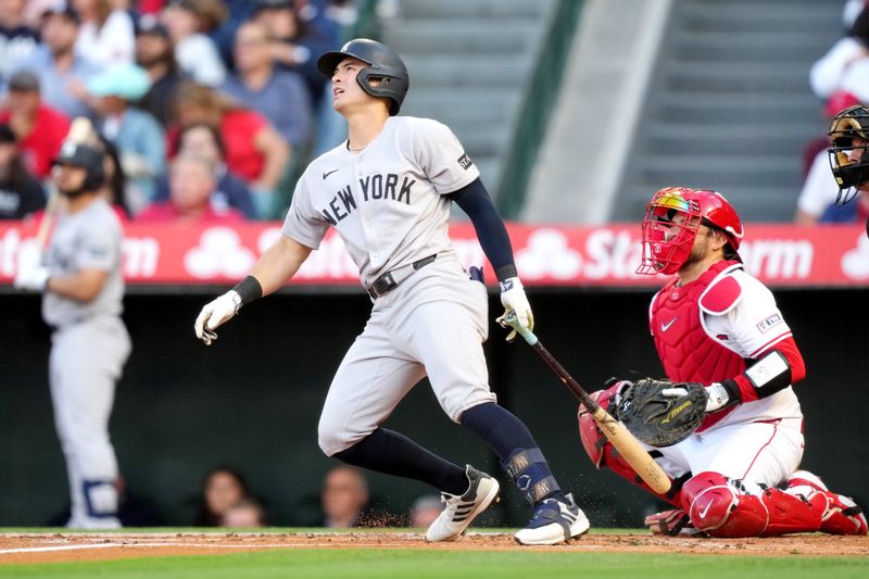 May 28, 2025; Anaheim, California, USA; New York Yankees shortstop Anthony Volpe (11) hits a RBI sacrifice fly ball in the fist inning as Los Angeles Angels catcher Travis d'Arnaud (25) watches at Angel Stadium. Mandatory Credit: Kirby Lee-Imagn Images