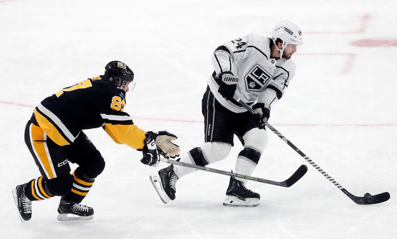 Feb 18, 2024; Pittsburgh, Pennsylvania, USA;  Los Angeles Kings center Phillip Danault (24) moves the puck against Pittsburgh Penguins center Sidney Crosby (87) during the second period at PPG Paints Arena. Los Angeles won 2-1. Mandatory Credit: Charles LeClaire-USA TODAY Sports