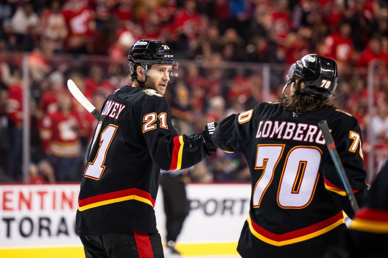 Nov 23, 2024; Calgary, Alberta, CAN; Calgary Flames center Kevin Rooney (21) celebrates with left wing Ryan Lomberg (70) after scoring a goal against the Minnesota Wild during the first period at Scotiabank Saddledome. Mandatory Credit: Brett Holmes-Imagn Images